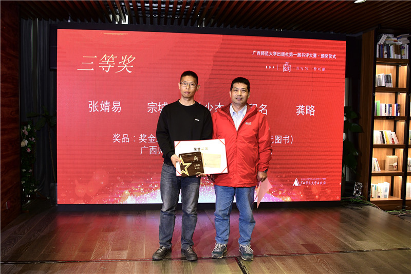 廣西師范大學(xué)出版社集團(tuán)首席編輯沈偉東（右）為三等獎(jiǎng)獲得者孫少杰頒發(fā)獎(jiǎng)牌及榮譽(yù)證書（李顯楊攝）.jpg