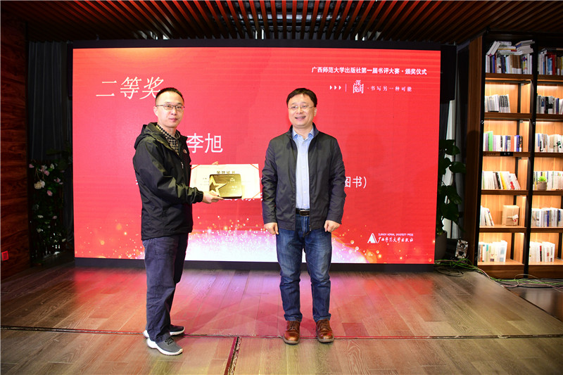 廣西師范大學(xué)出版社集團(tuán)董事長(zhǎng)助理張俊顯（右）為二等獎(jiǎng)獲得者王棟頒發(fā)獎(jiǎng)牌及榮譽(yù)證書（李顯楊攝）.jpg